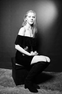 Portrait of female model sitting on seat against wall