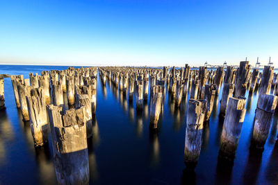Panoramic view of wooden posts at princes pier in sea against clear blue sky