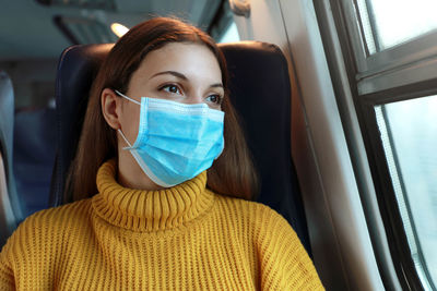 Young woman in mask sitting at bus