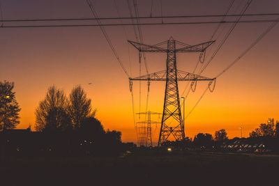 Low angle view of silhouette electricity pylon against sky during sunset