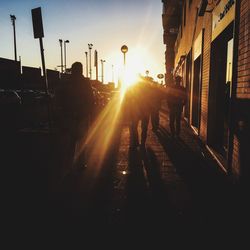 Silhouette people on road against sky during sunset