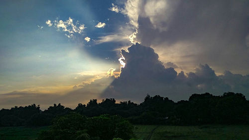 Low angle view of storm clouds over silhouette landscape