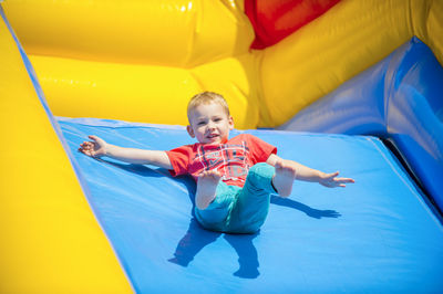 Low angle portrait of boy sliding on bouncy castle