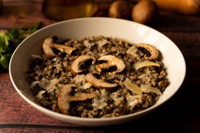 Mushroom risotto, italian food known as risotto ai funghi, closeup with warm light, parsley, side 