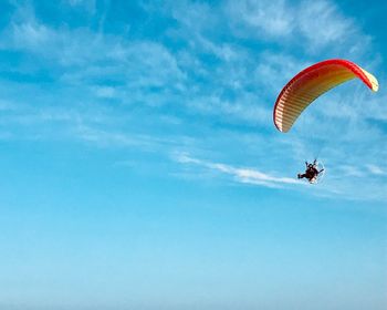 Low angle view of person paragliding against sky