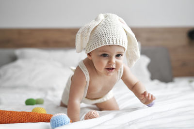 Cute boy crawling on bed at home