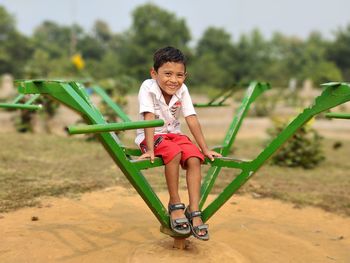 Young boy sitting on a carousel with green blur background. cute smiling 5 years teen boy portrait