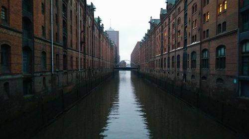 Canal in city against sky