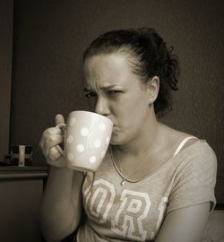 Portrait of mid adult woman having coffee while sitting at home