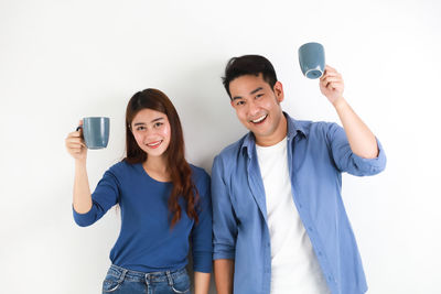 Portrait of smiling young woman photographing against white background