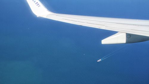 Airplane flying over sea against blue sky