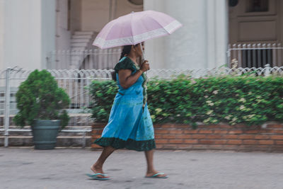 Full length of woman with umbrella standing in rain