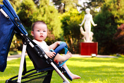 Portrait of boy sitting stroller at park