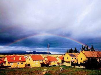 Rainbow over houses and buildings against sky