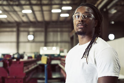 Manual worker wearing protective eyeglasses while looking away in steel industry