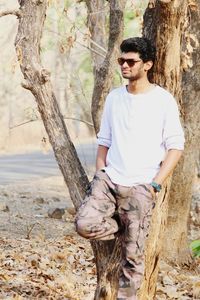 Young man leaning on tree trunk