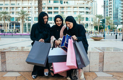 Cheerful women wearing shopping bags standing outdoors