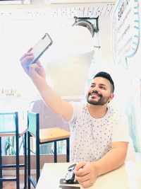 Portrait of young man using mobile phone on table