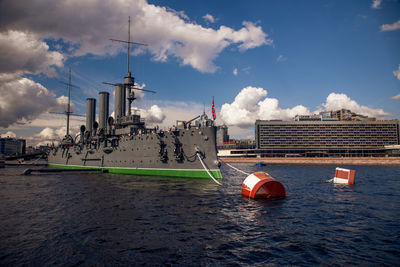 Boats moored on river in city against sky