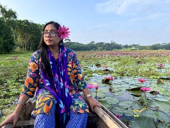 Portrait of young woman standing by lake