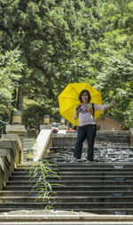 Full length of man standing on yellow umbrella