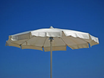 Low angle view of parasol against blue sky