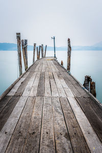 Wooden jetty on pier over sea against sky