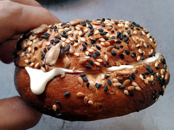 Cropped hand of person holding bagel with cream cheese