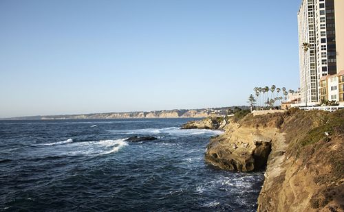 Scenic view of la jolla cove by buildings against clear sky