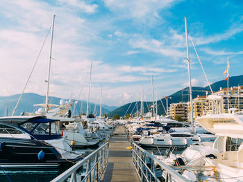 Sailboats moored at harbor against sky