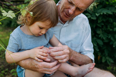 A little girl hugs her grandfather on a walk in the summer outdoors.