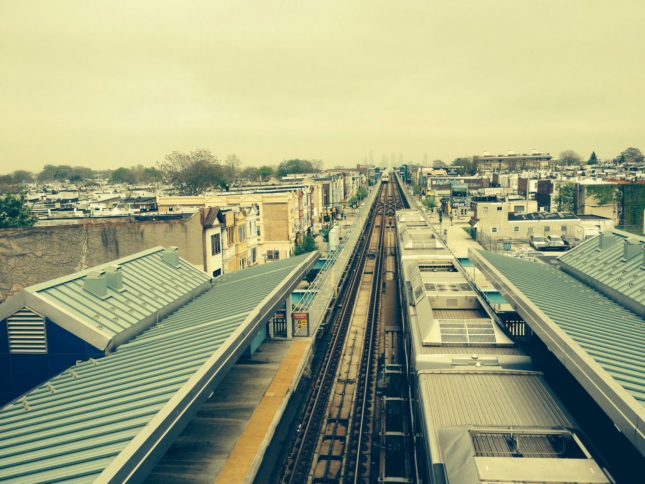 railroad track, architecture, building exterior, built structure, transportation, rail transportation, high angle view, city, public transportation, railroad station, diminishing perspective, clear sky, the way forward, railroad station platform, sky, railway track, vanishing point, residential building, city life, residential structure