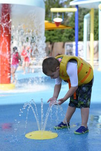 Full length of playful boy by fountain at water park