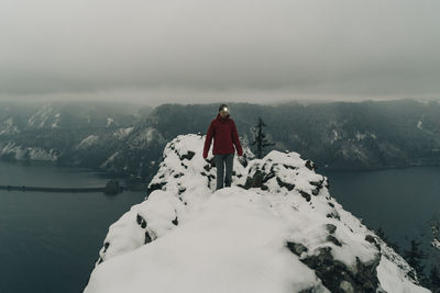 Man standing on mountain against sky during winter