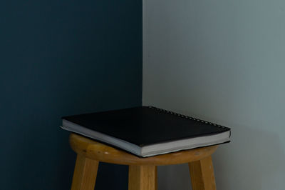 Close-up of open book on table against wall