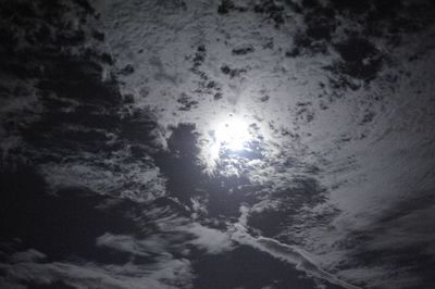 Low angle view of sun shining through clouds