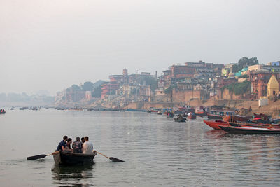 People on boat in sea against sky