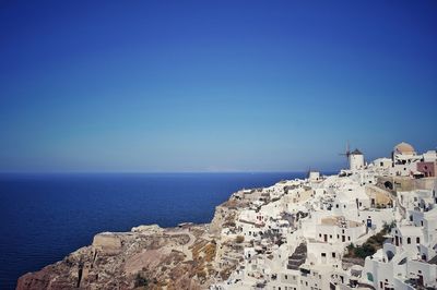 High angle view of town by sea against clear blue sky