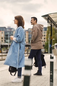 Side view of man and woman waiting at tram station