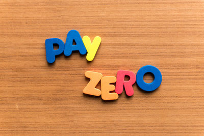 High angle view of colorful pay zero text on wooden table