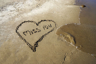 High angle view of text on heart shape on sand