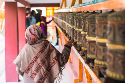 Woman touching praying wheel in temple