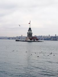 View of city at waterfront against cloudy sky