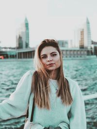 Portrait of young woman standing against city in water