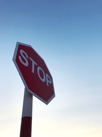 Low angle view of road sign against blue sky