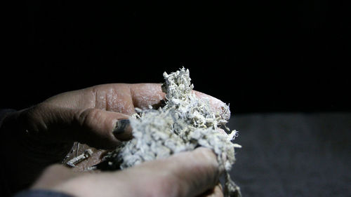 Close-up of man holding hand over black background