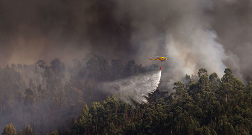 Firefighter helicopter fighting against a forest fire during day in braga, portugal.