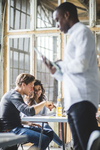 Smiling computer programmers using laptop while businessman standing in foreground at creative office