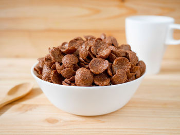 Chocolate breakfast cereal in a white bowl on wooden table. healthy breakfast concept.