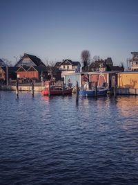 Houses by river against clear sky